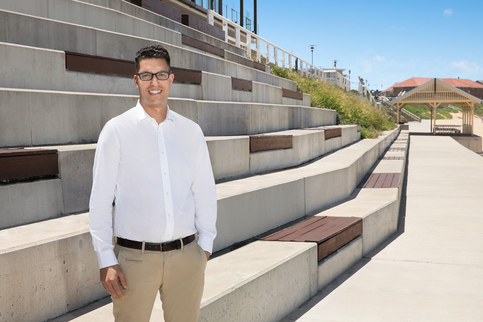 Ross Sergi, mortgage broker, standing on the steps at Newcastle beach, NSW